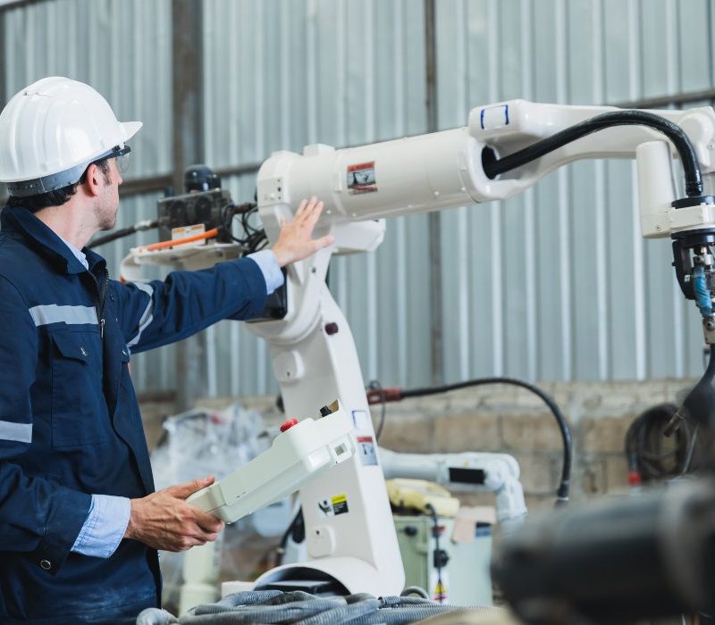 engineer controlling robot arm at factory. checking the operation of robot arm. Technology, automation, innovation and engineering concept.